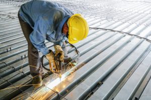 Steel deck framing by worker with a hard hat on and power tool